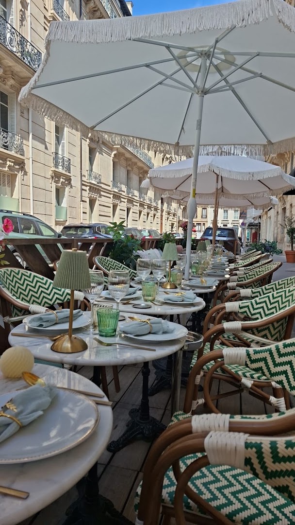 La terrasse vide aux tables dressées sous des parasols blancs